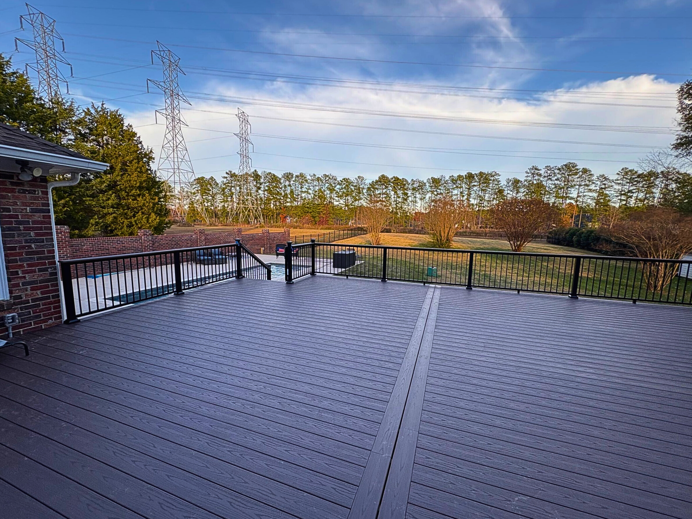 Expansive custom composite deck in Matthews, Nc with aluminum rails overlooking a forest.